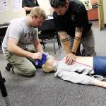 Kole Kellison, left, and Capt. Jerry Helm perform a demonstration with Central Whidbey Island Fire and Rescues new high-tech CPR dummy. Fire commissioners watched a display of the dummys simulated vitals change as the two provided treatment. Photo by Laura Guido/Whidbey News-Times