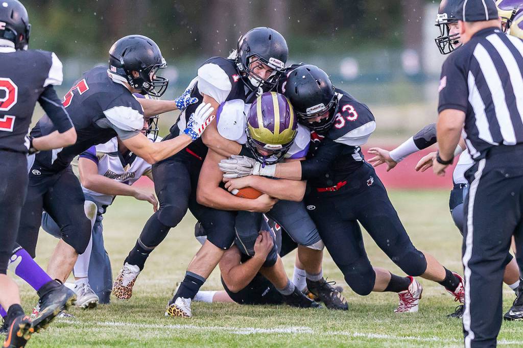 Sean Toomey-Stout (1) and Gavin Knoblich (33) lead a gang of Coupeville tacklers bringing down a Wolverine.(Photo by John Fisken)