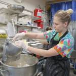 Candi Rosendahl feeds coconut oil to a shredding machine, a key ingredient to the pie crusts.