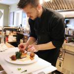 Sous Chef Kyle Campbell puts the finishing touches on his seared pork belly with zucchini fritters, broccolini and a grainy mustard sauce. He developed the special thats become a favorite among customers at Frasers Gourmet Hideaway in Oak Harbor. Photo by Laura Guido/Whidbey News Group