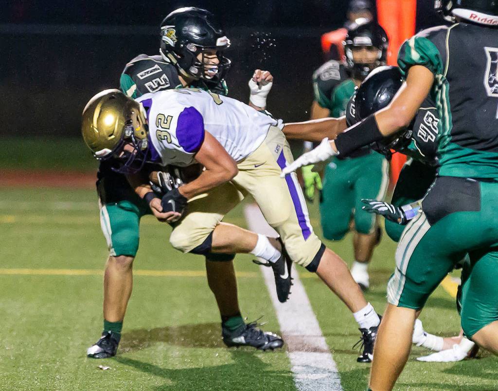 Oak Harbors Jake Mitten blasts through the tackle of Dylan Rice (13) for one of his three touchdowns.(Photo by John Fisken)