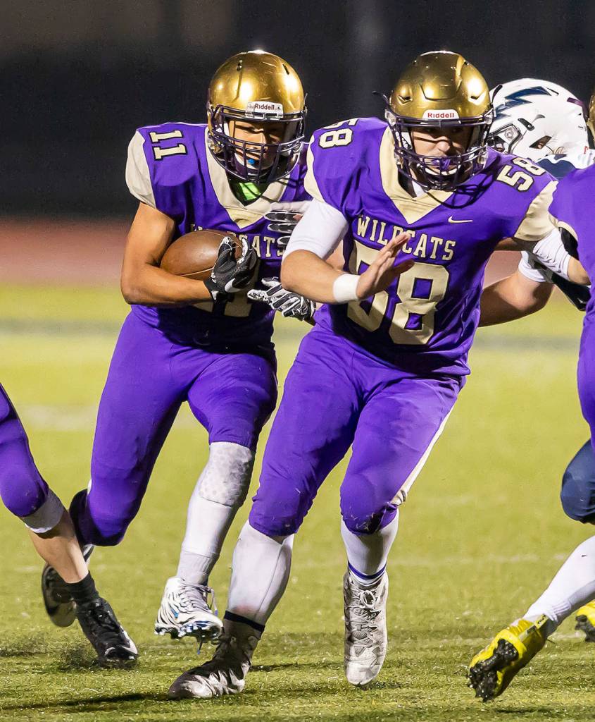 Aaron Martinez (11) runs behind the block of Brandon McCollough (58). (Photo by John Fisken)