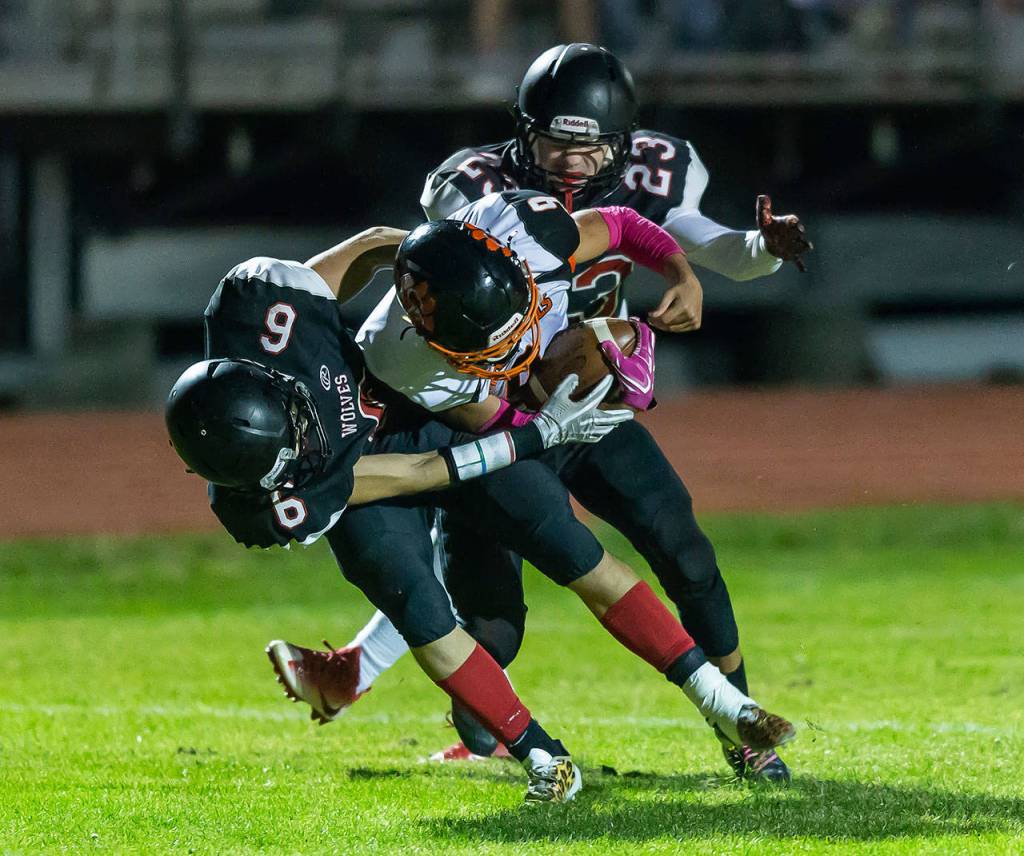 Sean Toomey-Stout (6) and Ben Smith (23) wrestle Mason McBride to the ground.(Photo by John Fisken)