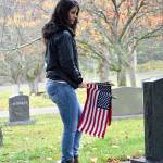 Andrea Kunze looks for gravestones belong to veterans to place a flag near. She and other volunteers participated in the annual event held by the Whidbey Island Military Officers Association to honor fallen service members Saturday morning at Maple Leaf Cemetery in Oak Harbor. Photo by Laura Guido/Whidbey News-Times