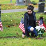 Alexis Kunze, a freshman NJROTC member, plants a flag near the grave of a deceased veteran Saturday at Maple Leaf Cemetary. Photo by Laura Guido/Whidbey News-Times