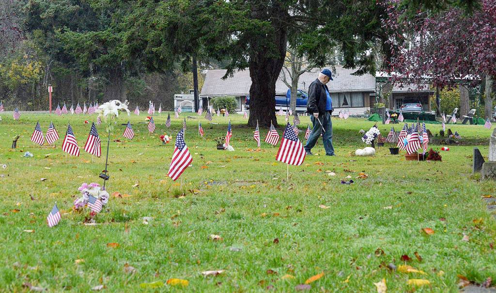 Ed Hickey walks among the many flags planted near the graves of veterans at Maple Leaf Cemetery in Oak Harbor. Hickey, other members of the Oak Harbor Military Officers Association of America and NJROTC volunteers placed over 500 flags across the island. Photo by Laura Guido/Whidbey News-Times