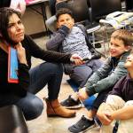 Volunteer reader Claudia Sámano Losada reacts to an answer given by Grayson Wolniakowski, center, Tuesday night at Oak Harbor Librarys Prime Time reading program. Jaime Abreu Serrano, left, and Josh Matro giggle in response. Photo by Laura Guido/Whidbey News-Times