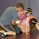 Oak Harbor girls wrestling coach Brian Farmer offers instruction to Laura Gudgel, top, and Nicole Sipes during practice this week. (Photo by Jim Waller/Whidbey News-Times)