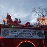 Photos by Maria Matson / Whidbey News Group.                                 Santa Claus, known as Paul Messner when off-duty, waves to the crowd on a decked-out fire truck.