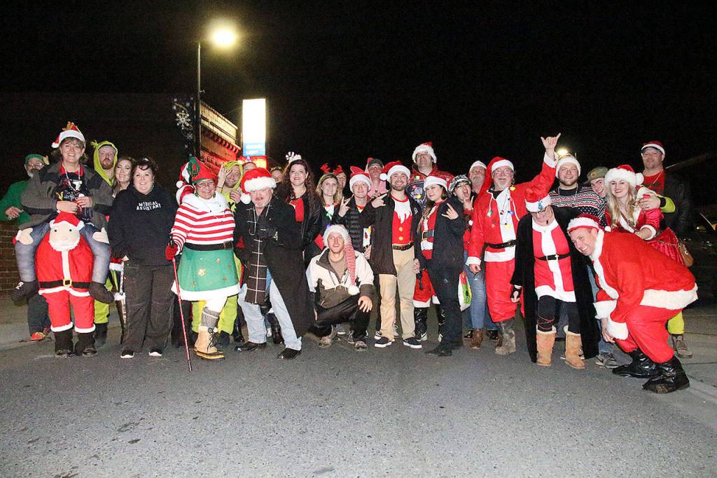 The group of Santas, Grinches, elves and more gather on Pioneer Way toward the beginning of the annual Santa pub crawl. The participates collected over 200 food items for the North Whidbey Help House at the beginning of the night. Photo by Laura Guido/Whidbey News-Times