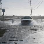 A pickup powers through the flooded Keystone Avenue Thursday. Water surged over the land in the area during the wind storm, crossing the road and hitting houses. Photo by Laura Guido/Whidbey News-Times