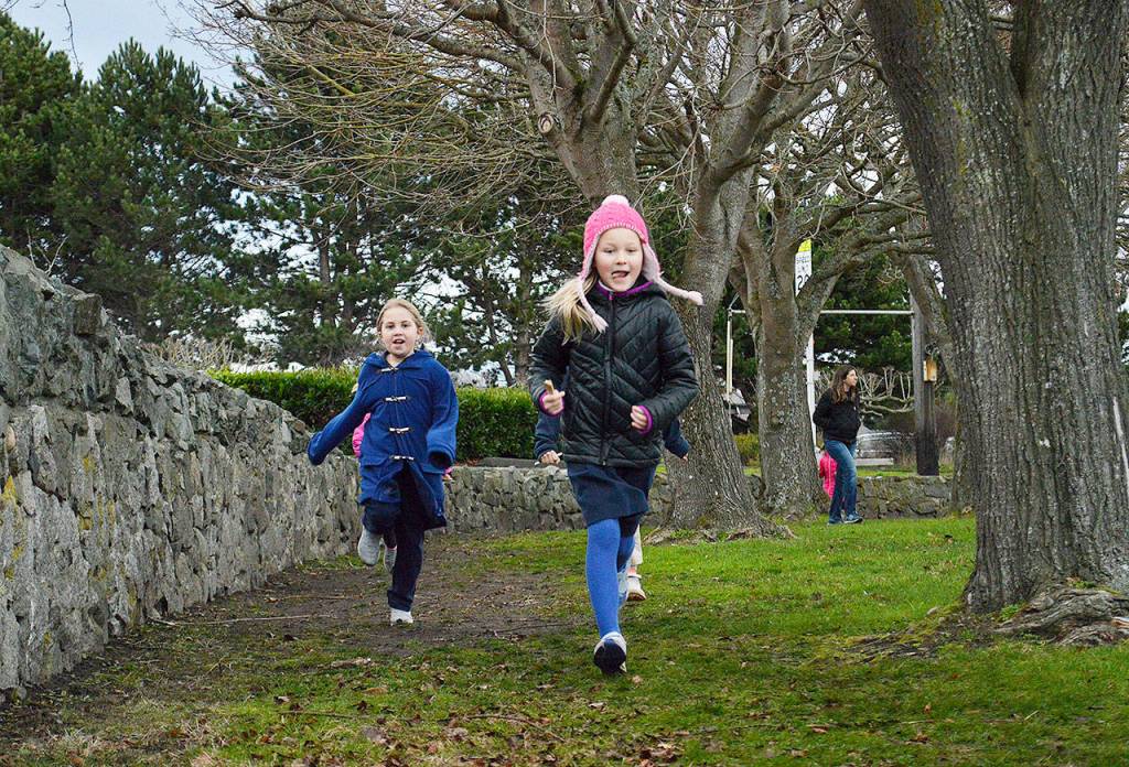 Kylie Hawkins, left, and Katrin Kurganov finish a lap strong. Students receive a Popsicle stick after a lap to keep track of how far they go. Photo by Laura Guido/Whidbey News-Times