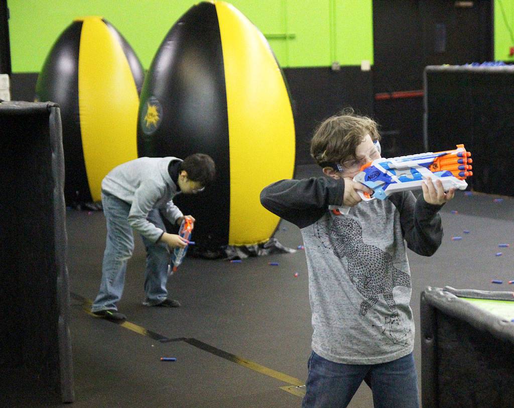 Skyler Famoso takes aim while Aksel Denney reloads Saturday at the Nerf gun arena on Goldie Street. Photo at right,Famoso, 9, charges his opponents. Photo by Laura Guido/Whidbey News-Times