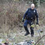 Officer Mel Lolmaugh, Oak Harbor Police Department, carefully steps over the trash in an area known as The Pit off of Goldie Road. Photo by Laura Guido/Whidbey News-Times