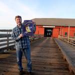 Scott Rosenkranz holds up his design for the 2019 Musselfest poster. The festival will be held March 2-3 in Coupeville. (Photo by Maria Matson/Whidbey News-Times)