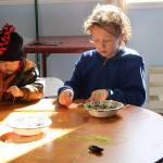 Lucas, 2, at left, and Tevian, 9, have fun Sunday creating seashell-and-bead necklaces at the childrens craft table at the Coupeville Masonic Lodge. (Photo by Maria Matson/Whidbey News -Times)