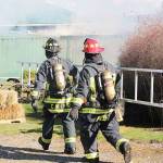 Firefighter/EMT, John Lloyd, front, and Lt. James Meek, with Central Whidbey Island Fire and Rescue carry a ladder to a storage container. The hay inside caught fire Tuesday. Photo by Laura Guido/Whidbey News-Times