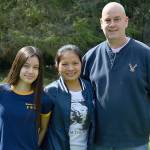 Lottery winner Brian Kutz, with daughter Kendra, left, and wife, Tuk, stand outside their Coupeville home. Photo by Laura Guido/Whidbey News-Times