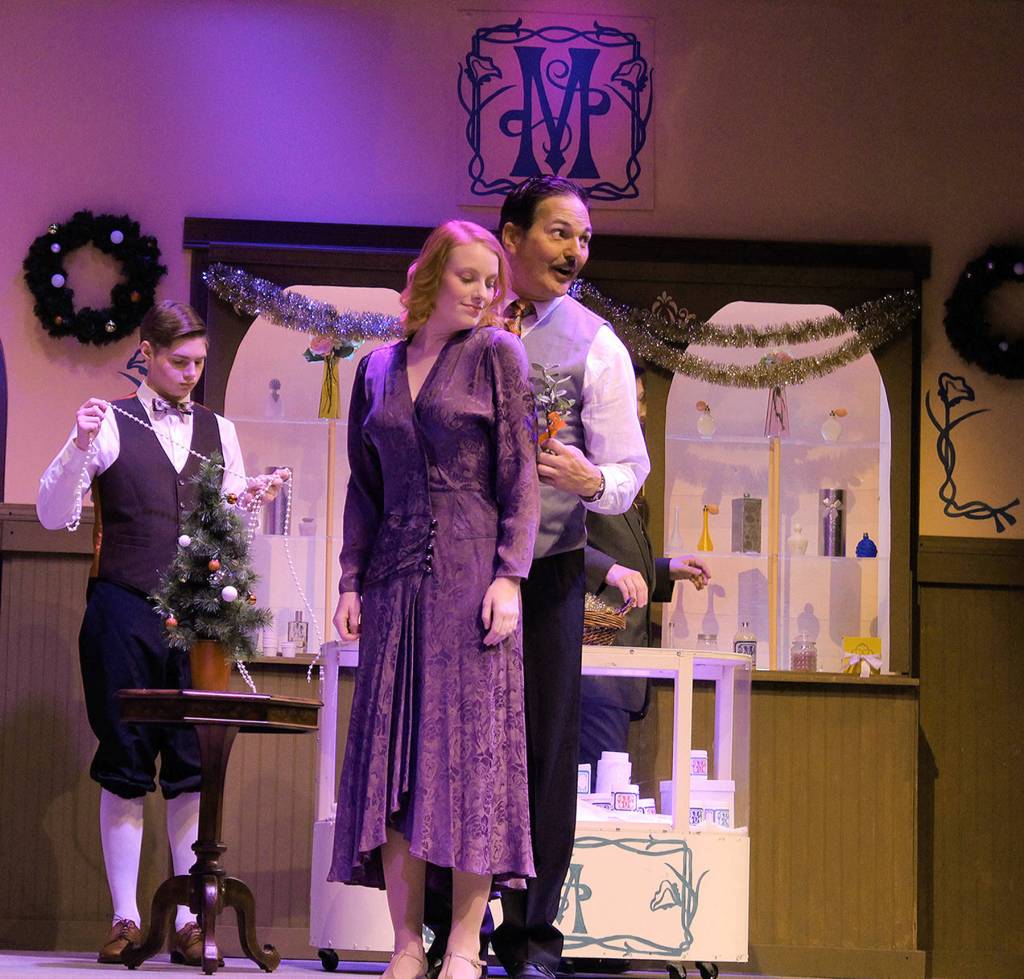 Delivery boy Arpad Laszlo, played by Carl Davis, decorates the store while sales associate Steven Kodaly (Douglas Langrock) moves mistletoe closer to Ilona Ritter (Emily Hoyt.)