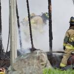 North Whidbey Fire and Rescue firefighters Dave Hanson and Stephanie Mace clear out a burning storage building Monday morning. Photo by Laura Guido/Whidbey News-Times