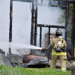 North Whidbey Fire and Rescue firefighter Stephanie Mace works to extinguish the last flames on a chicken coop that caught fire Monday morning. Photo by Laura Guido/Whidbey News-Times