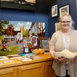 Events Manager Vicki Graham holds an oversized pair of Dutch wooden shoes. In the background are Holland Happening- related items lent for display by the community.                                (Photo by Maria Matson)