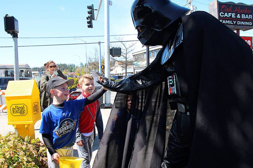 A high five from the dark side: Darth Vader, also known as Christian Vasileff of Oak Harbor, high fives six-year-old Dylan Sculley as four-year-old Blake Boyer smiles after a high-five of his own.