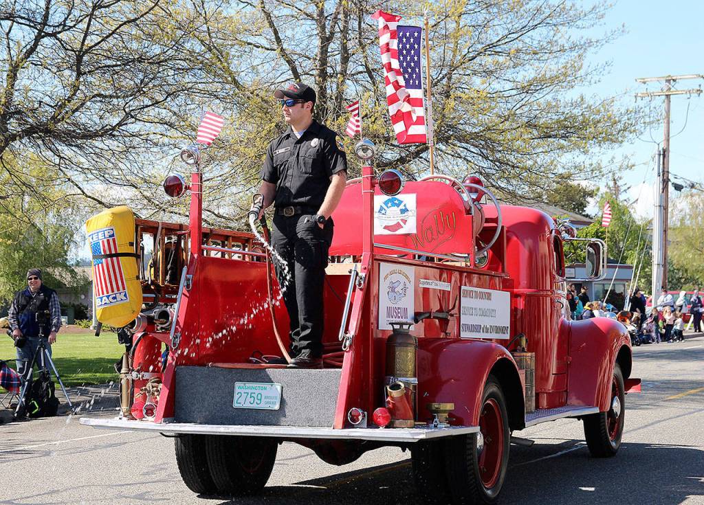 Oak Harbor Fire Department firefighter Dallas Brodt casually hoses down the street at the beginning of Saturdays Holland Happening parade, which was swept immediately after by the traditional street sweepers.