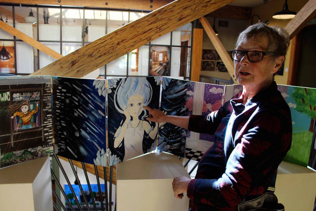 Peggy Gilmer looks over a ten-panel piece called Unhinged Reflections by Coupeville High School student Casey Rogers at the Art with a Message exhibit. On view until June 9 at Bayview Cash Store, the annual all-island high school art show is sponsored by Goosefoot. Photo by Patricia Guthrie/Whidbey News Group