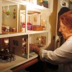 Shirley Viall adjusts furniture located in the kitchen of the miniature dollhouse created by Lyn DeShong.