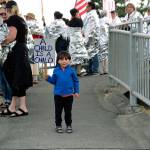 Demonstrators in Coupeville Friday evening hold up signs protesting immigration policies as part of a national Lights for Liberty event. Everson Welch, 3, attended with his family. (Photo by Maria Matson/Whidbey News-Times)
