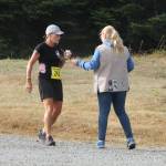 A volunteer helps a runner at a water station during last years Race the Reserve. More volunteers are needed to help with this summers event. (Photo by Jim Waller/Whidbey News-Times)
