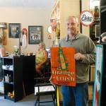 Matt Shorey holds one of his favorite items in the store, a vintage sign, as Tina Shorey talks with family member Kenzie Furman-Allen. (Photo by Maria Matson/South Whidbey-Record)