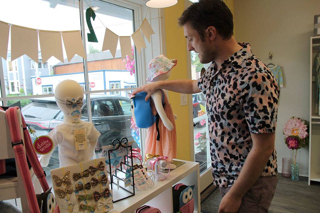 Christian Chambers arranges a display item in the front window of his new Coupeville store. (Photos by Maria Matson/Whidbey News-Times)