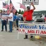 Paul Patterson, foreground, waves as cars pass by during a rally to support the Navy Saturday in Oak Harbor.