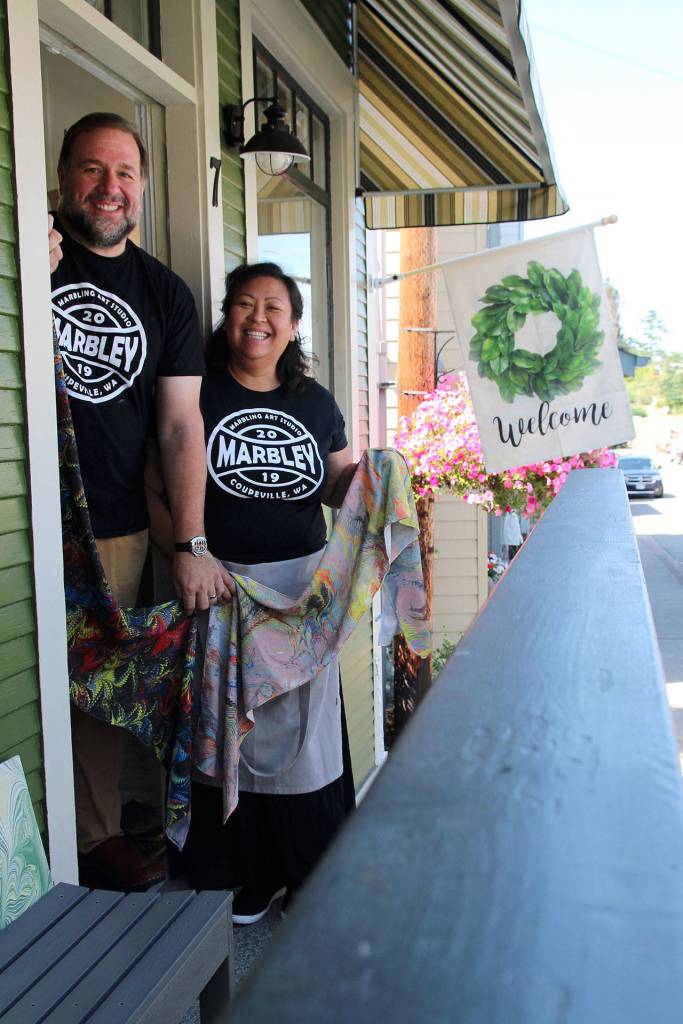 Coupeville residents and married couple Ed Hodson and Joan Samson stand in front of their new studio, Marbley. They hold a few of the many scarves theyve created.