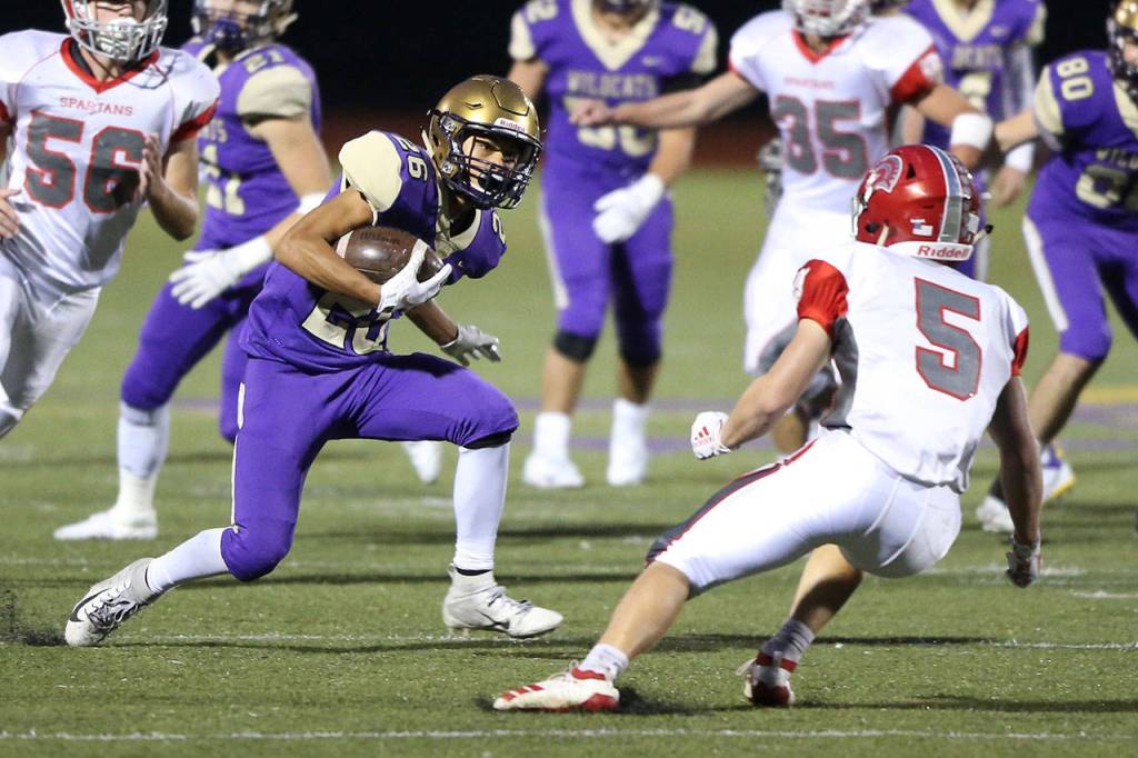 In the photo above, Oak Harbor running back Brenden Andersen (26) sets up Stanwood defender Ryder Baumgarner; then below, Andersen leaves Bumgarner sprawling on the way to a big gain.(Photos by John Fisken)
