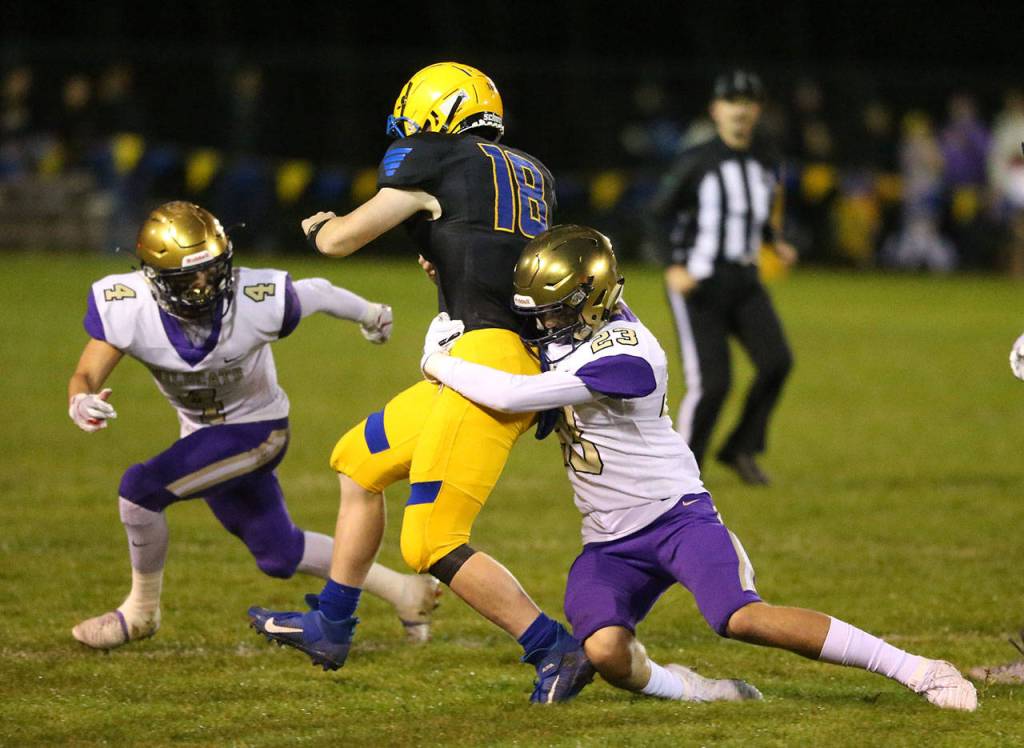 Oak Harbors Aaron Linden tackles Ryan Pelton (18) as Landon Cantrell (4) closes in.(Photo by John Fisken)