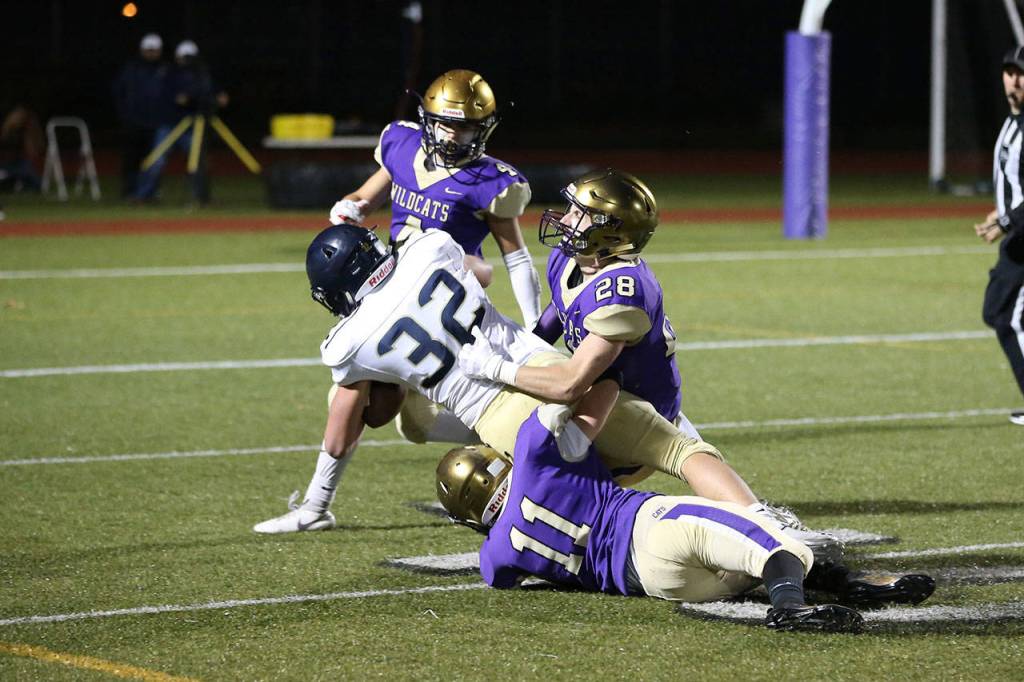 Oak Harbors Luke Golden (11) and Gabriel Daggett (28) haul down Arlingtons Jaden Roskelley.(Photo by John Fisken)