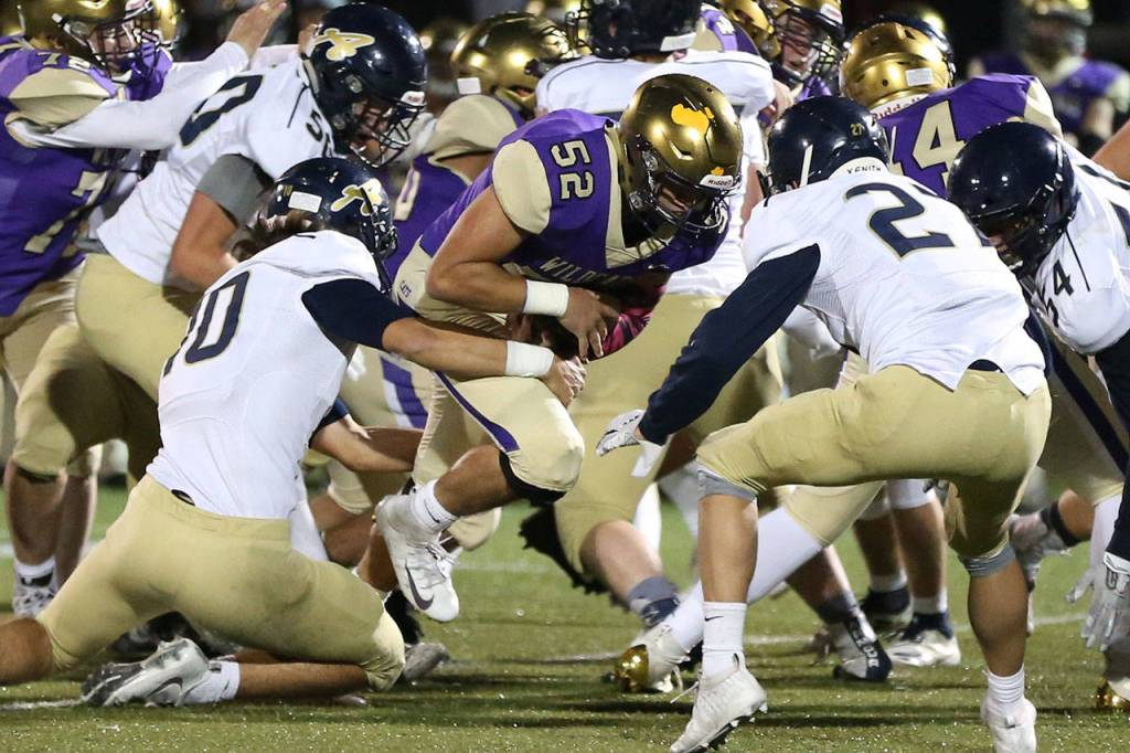 Oak Harbor Michael Gomez (52) bulls into the heart of the Arlington defense.(Photo by John Fisken)