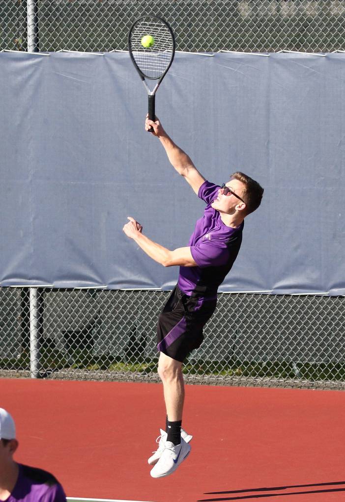 Micah Franklin launches a serve in Tuesdays district doubles action.(Photo by John Fisken)