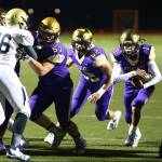 Oak Harbors Cameron Asinsin (1) runs through a hole created by Justin Campbell (57) and John Leete (74). (Photo by John Fisken)