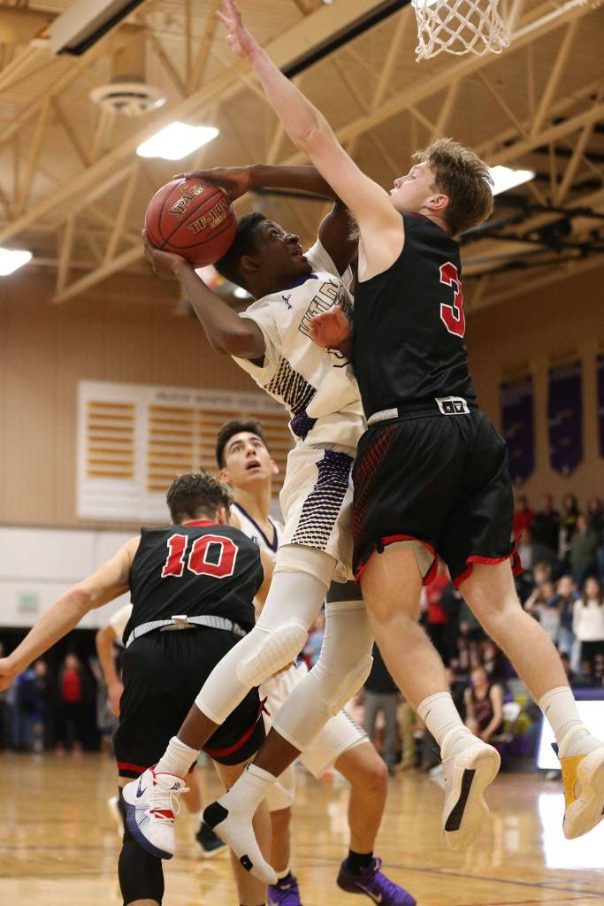 Oak Harbors Kenneth Tofah powers to the hoop against Coupevilles Mason Grove, right.(Photo by John Fisken)