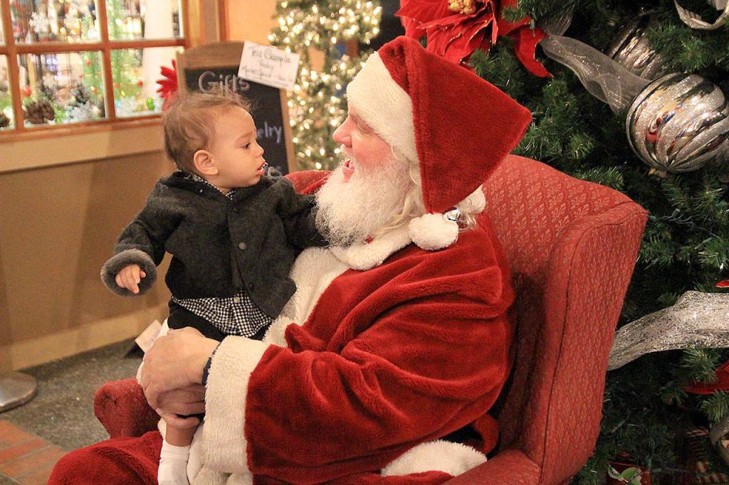 Marc-Henri Lunz scrutinizes Santas beard, which was real, Saturday evening in Oak Harbor at the Main Street Associations Home for the Holidays event.