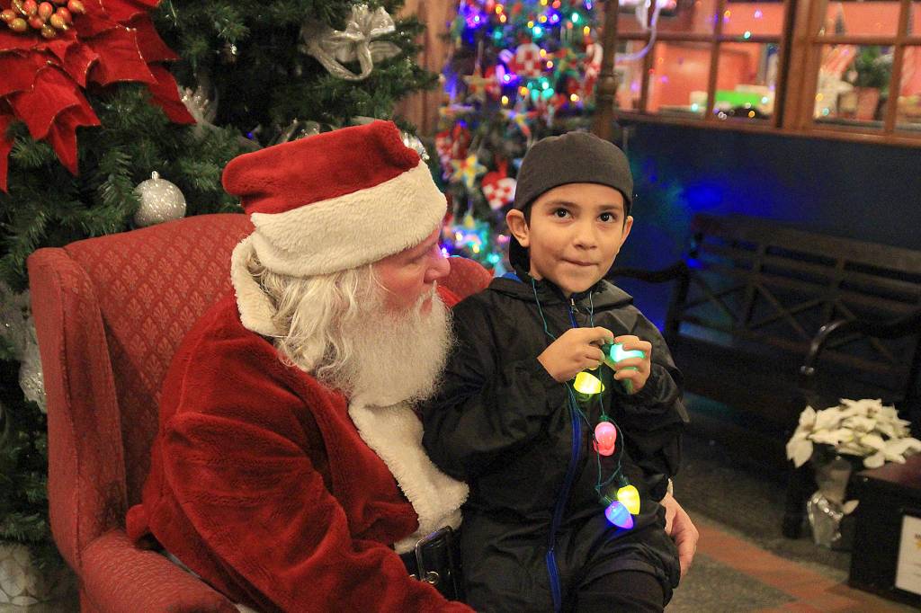 Photo at right, Aiden Feliu, 7, carefully ponders what he wants to ask for from Santa Saturday evening. He wants a Lego set.