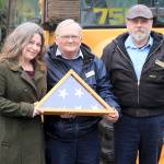 Memorial Day event organizer Kelly Davidson, Maple Leaf Cemetery Caretaker Mike Dougliss and Groundskeeper William West hold a flag that will be presented at this years event.