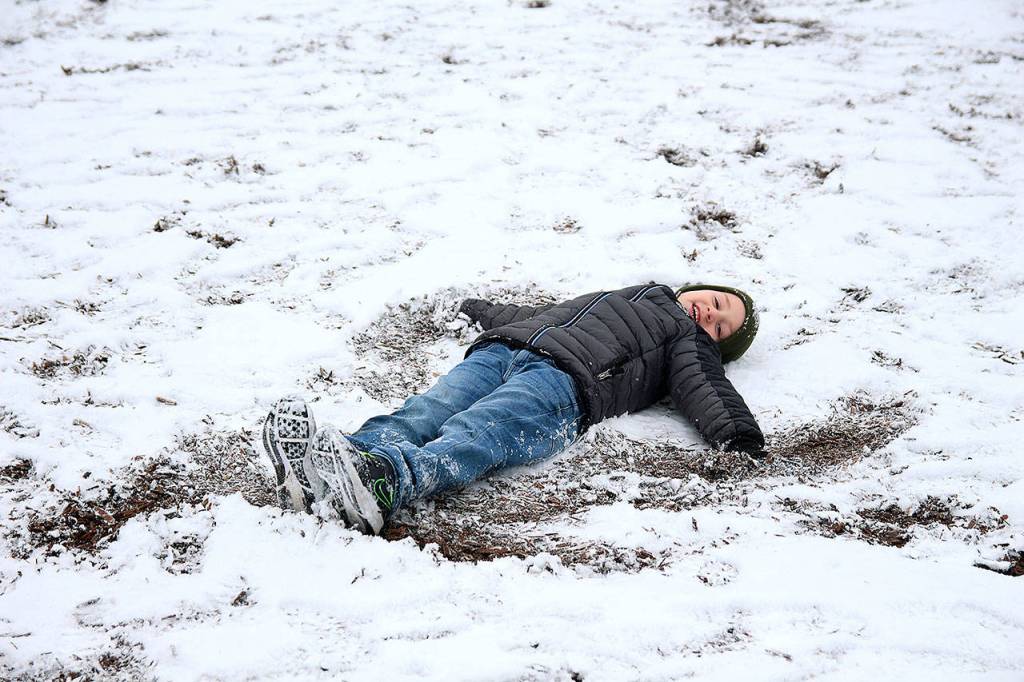 Jacob Daniels makes a snow-and-dirt angel Monday morning at Hillcrest Elementary School.