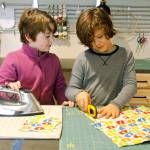 Arya Bochantin, left, irons a pattern while Rio Goette, right, cuts out patterns.