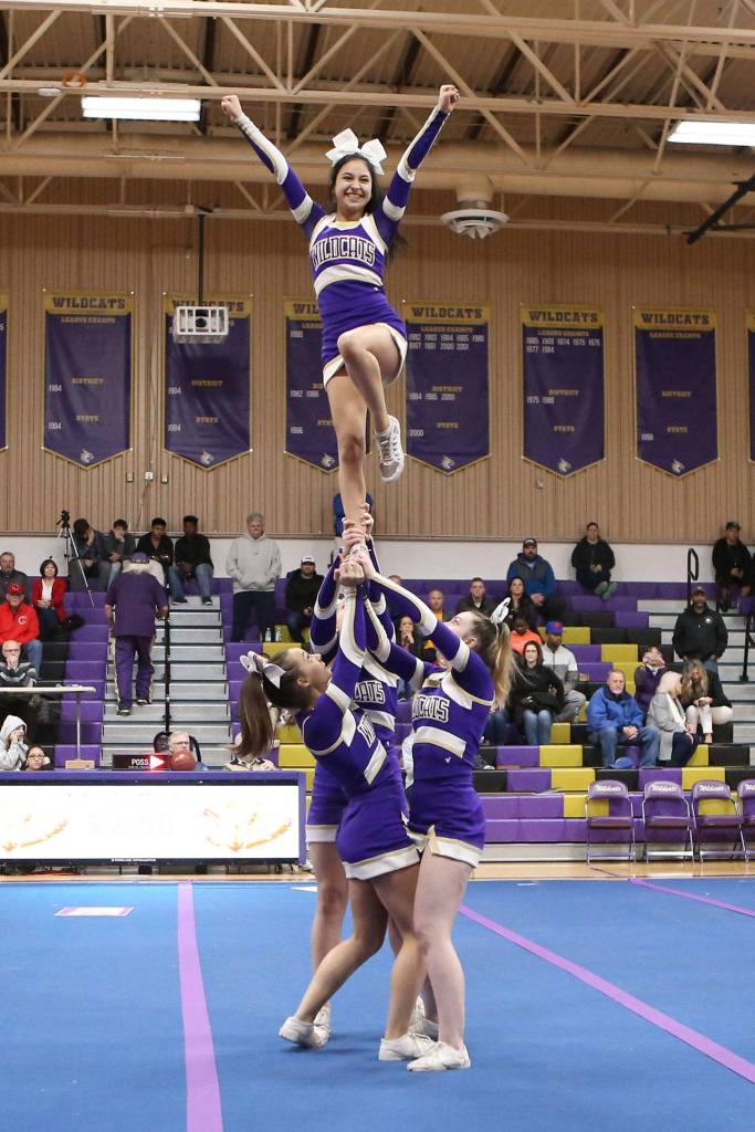 Photo by John Fisken                                Oak Harbors Alyssa Carlon, flyer; Jada Jones, left; Krystal Wyum, right; and Audrey Moyes perform at last Fridays basketball game.