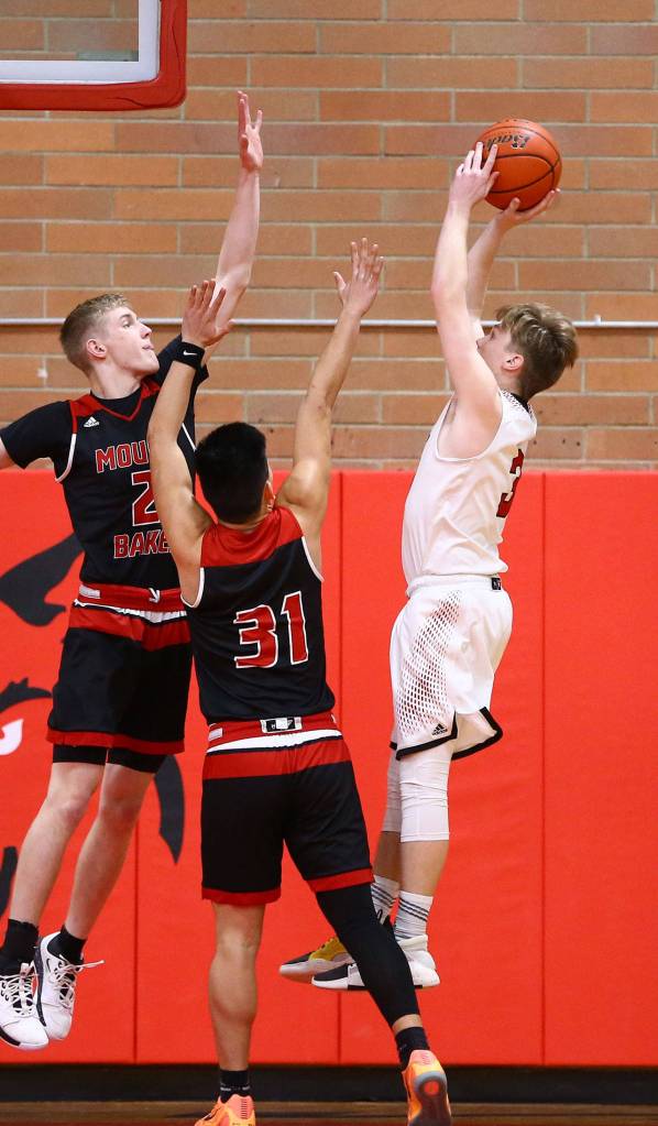 Mason Grove shoots a jump shot over Mount Bakers Garrett Smith, left, and Jason Lee (31).(Photo by John Fisken)